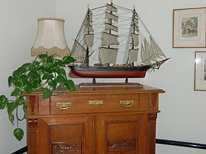 Kommode einer Bewohnerin oder eines Bewohners mit Segelschiffmodell und einer Pflanze darauf